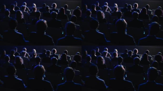 在黑暗的会议厅里，充满技术人员的观众观看了创新的鼓舞人心的主题演讲。商业技术峰会礼堂会议室挤满了代表
