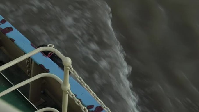 拖船显示出栏杆和水流尾流的汹涌波浪。