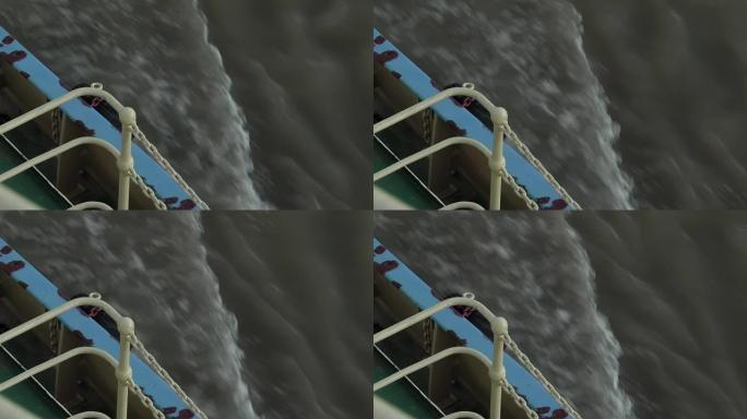 拖船显示出栏杆和水流尾流的汹涌波浪。