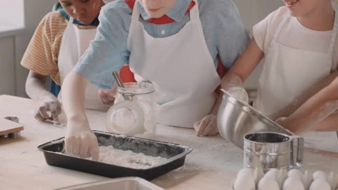 儿童在烤盘上倒面粉