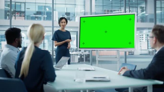 女性运营经理为一组经济学家举行会议演讲。亚洲女性使用带有水平绿屏模拟显示的数字白板。人们在商务办公室