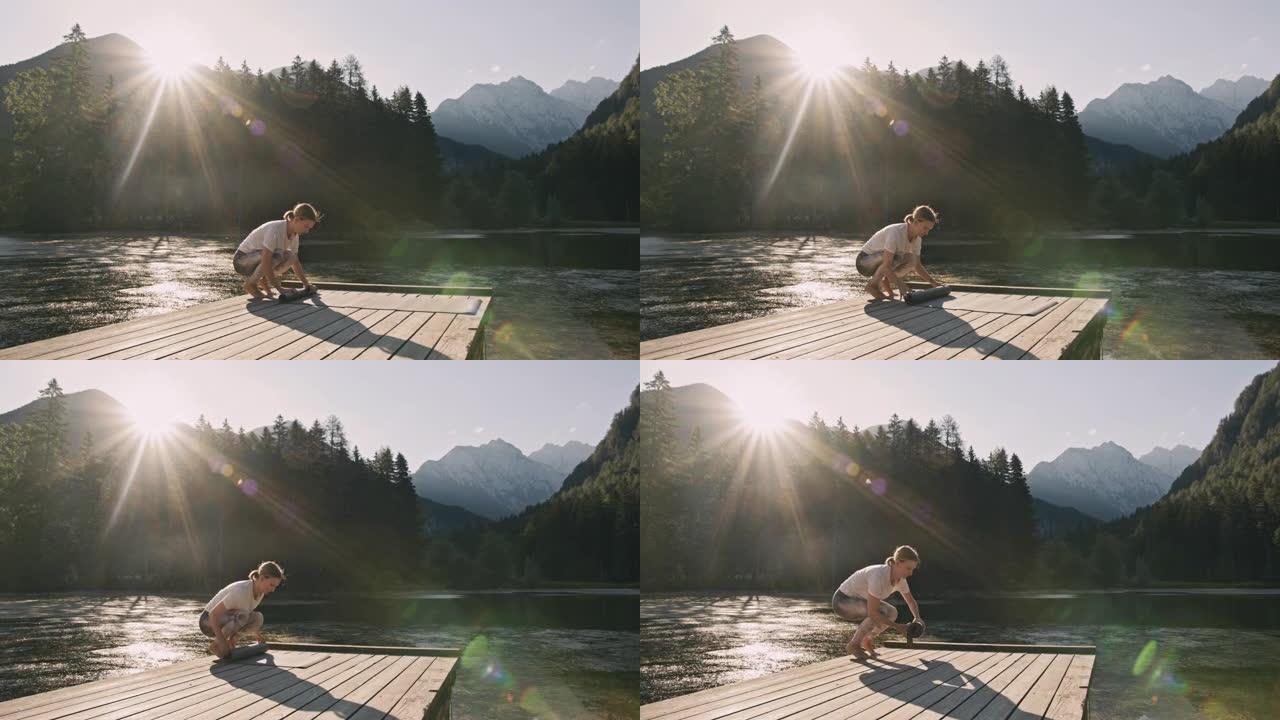 金发女人在杰泽斯科湖前的木板路上训练后，卷起瑜伽垫