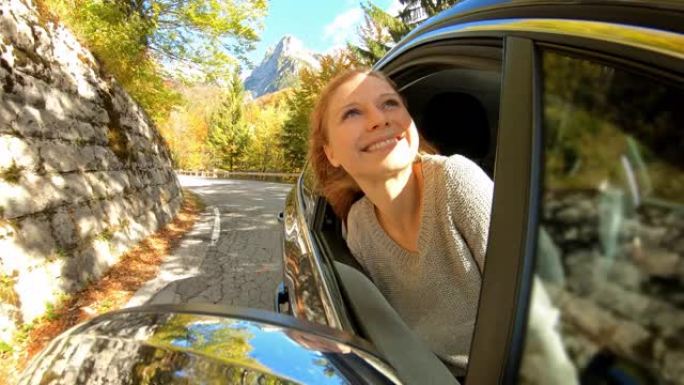 女人在温暖的秋日俯身从车窗外享受新鲜空气