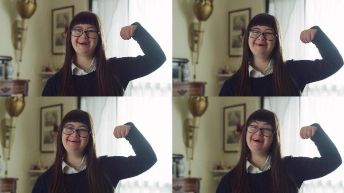 这张照片拍摄的是一个患有唐氏综合症的快乐友好的少女，她在家中用手臂和微笑展示着自己的力量。概念残疾人