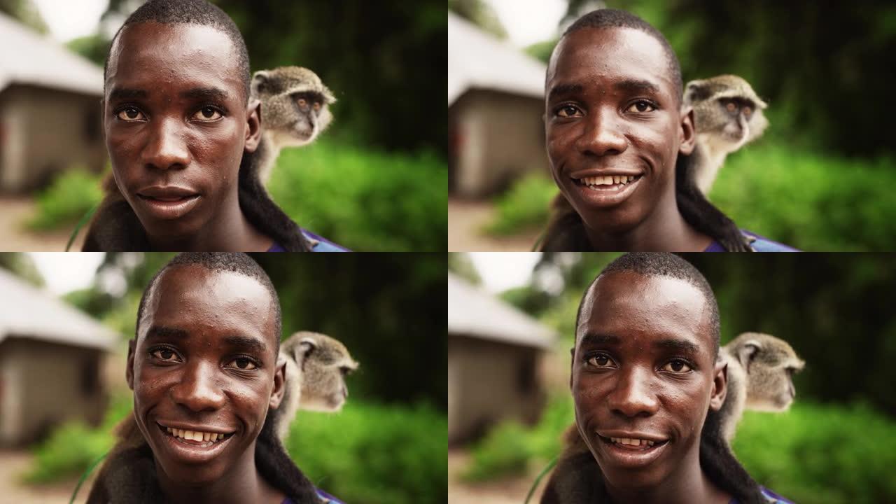 特写一幅真实的非洲男子的肖像，他背着一只小猴子看着相机，背景是绿色的微笑。带着幸福笑容的黑人友好男性