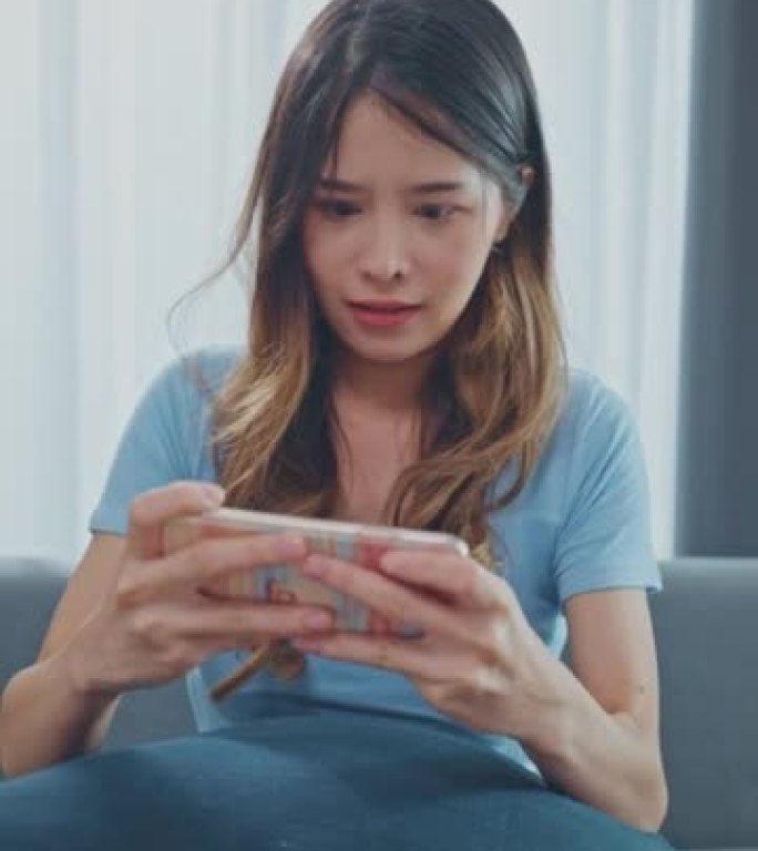 成功的亚洲女性在智能手机上玩电子游戏