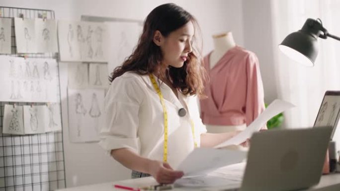 服装时装设计师在素描纸上寻找为她的项目选择草图并将其固定