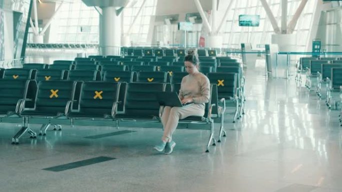 空荡荡的机场大厅，一名妇女在笔记本电脑上工作