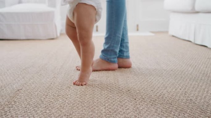 婴儿迈出第一步幼儿学习与母亲一起走路轻轻地帮助婴儿在家教孩子母亲信任