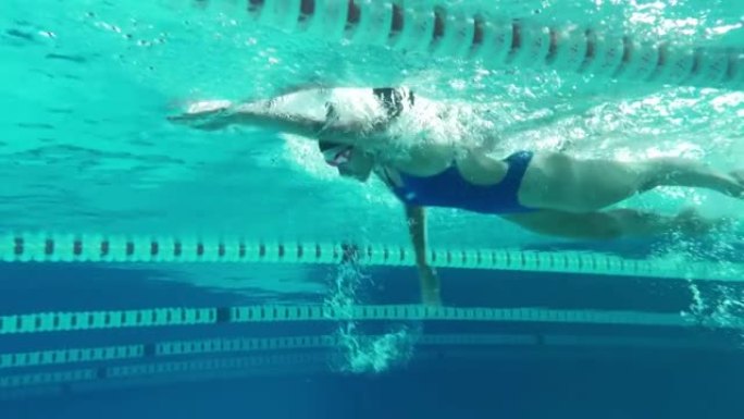 水下射击: 适合美丽的游泳者在游泳池里跑圈。职业女运动员以极快的速度游泳。准备创造世界冠军纪录。彩色