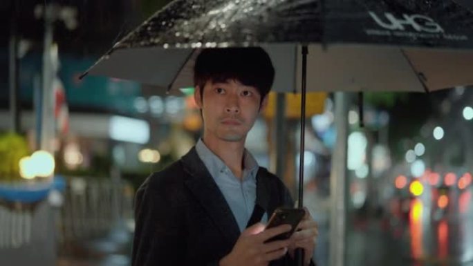 亚洲商人在雨天使用智能手机订购出租车