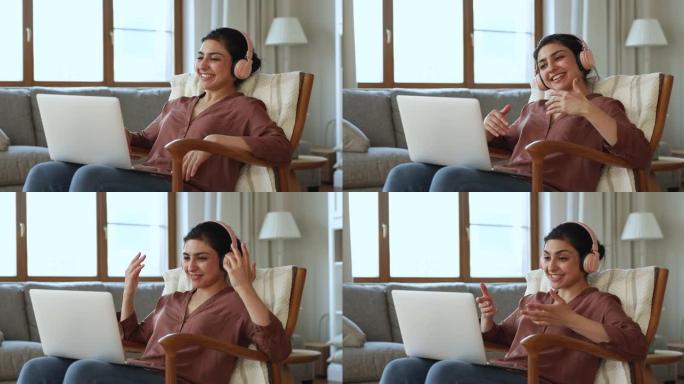 戴着耳机的印度女人斜卧在扶手椅上通过可视电话聊天