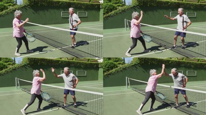 快乐的高加索高级夫妇在打了一场比赛后在室外网球场击掌