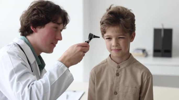 医生检查小男孩的耳朵，并击掌示意