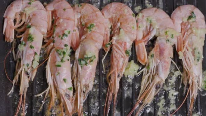 直视一排漂亮的粉红色虾，用大蒜黄油，欧芹和橄榄油在锅中煎炸