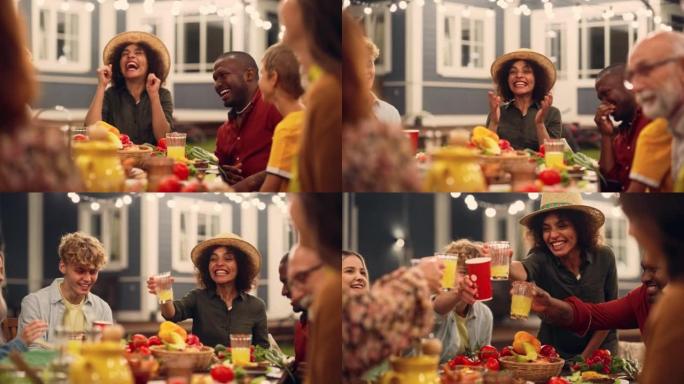 一位激动的年轻中东女性在户外餐桌上分享故事，开玩笑，大笑，与不同的亲戚和多民族朋友一起玩的肖像。碰杯