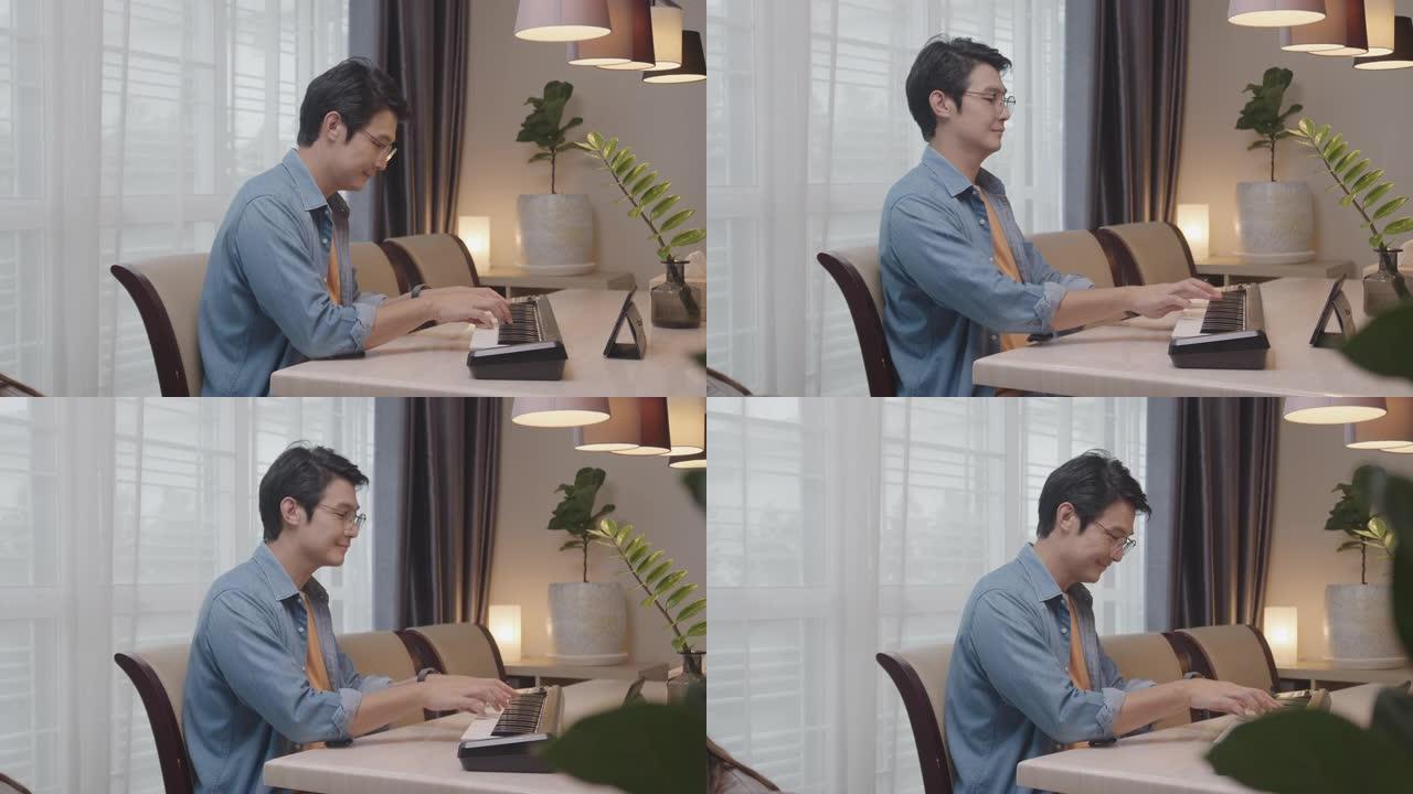 年轻的亚洲男性通过互联网上的视频通话与他的朋友在数字平板电脑上玩电子钢琴或键盘电话会议。玩音乐的人很
