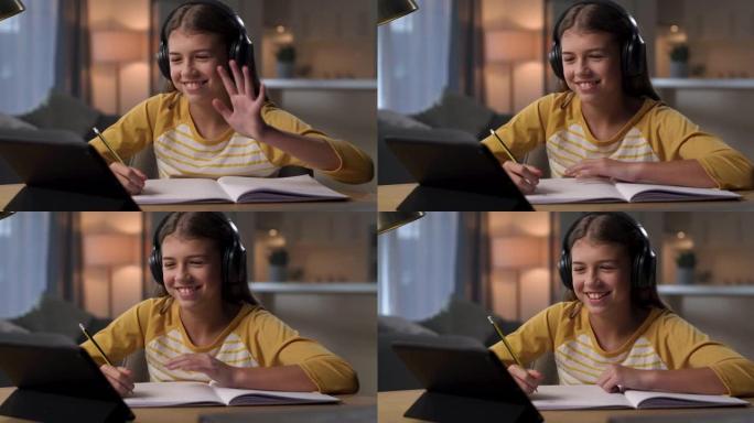 4k视频片段，一个年轻女孩坐在家里，戴着耳机，同时使用平板电脑进行电子学习