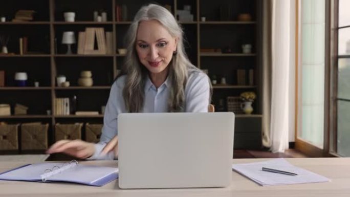 使用笔记本电脑在线研究退休的高级女性做笔记