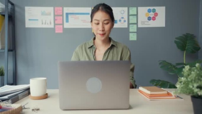 年轻的自由亚洲女士休闲服开放式笔记本电脑准备开始在办公室的木制办公桌上工作。在家工作，远程，远程教育