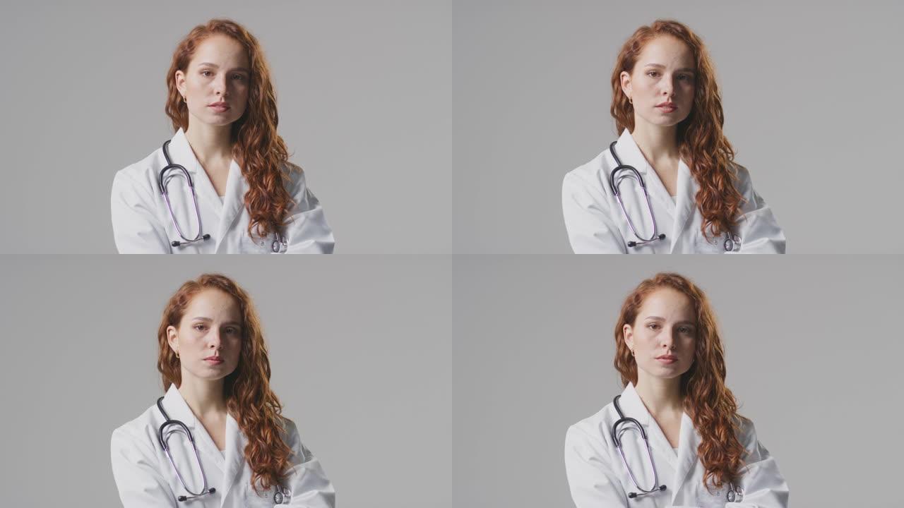 工作室肖像严肃的女医生与听诊器在白色外套在素色背景下