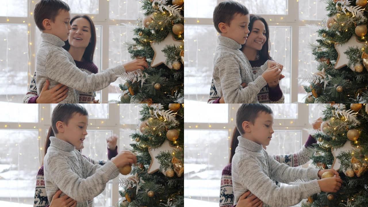 母亲和小儿子在圣诞树上挂球，在公寓里聊天