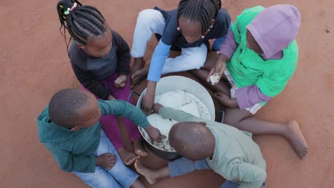 非洲的贫困。一小群饥饿的非洲黑人儿童从公共炊具中吃玉米