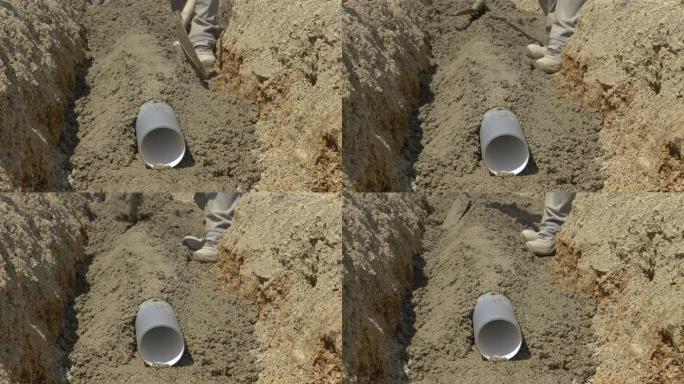 特写: 铺设在沟渠底部的塑料管上覆盖着新鲜的混凝土