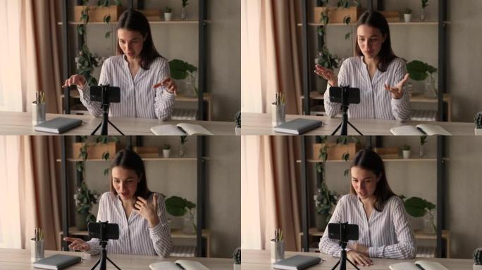 女人坐在桌子上使语音记录视频使用智能手机