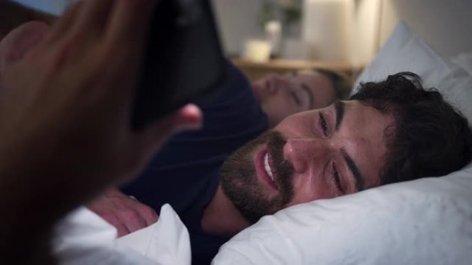 夫妻男子晚上躺在床上看手机屏幕