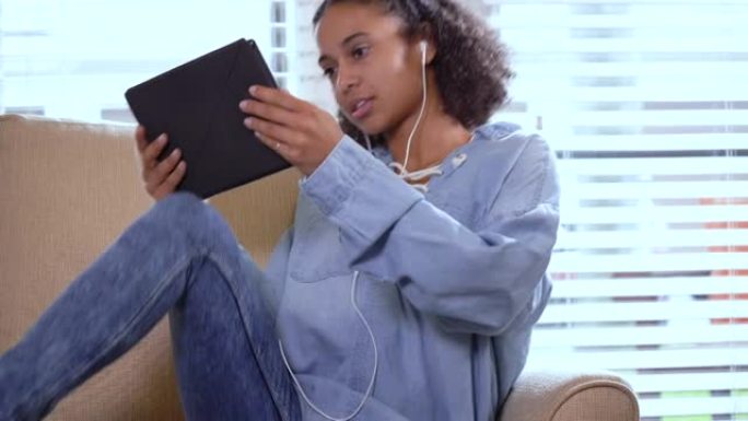 年轻的混血女人用数字平板电脑在家放松