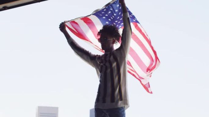 站在窗户附近时戴着墨镜的非洲裔美国男子举着美国国旗