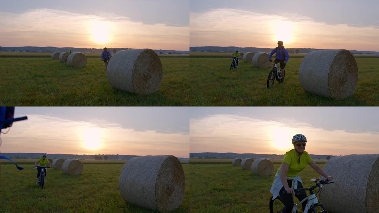 SLO MO夫妇骑自行车的人在日落时分在干草堆中骑山地自行车