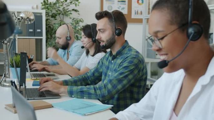 在呼叫中心工作的业务团队在办公室使用计算机在线咨询客户交谈和微笑