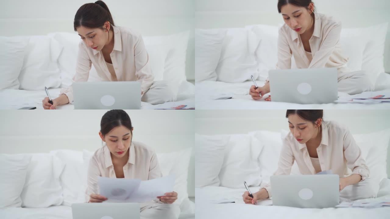 亚洲女商人使用科技平板电脑工作，并在床上写笔记本