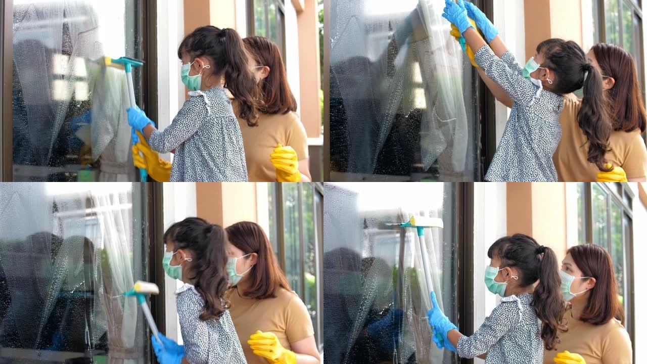 小女孩在母亲的帮助下清洁窗户玻璃