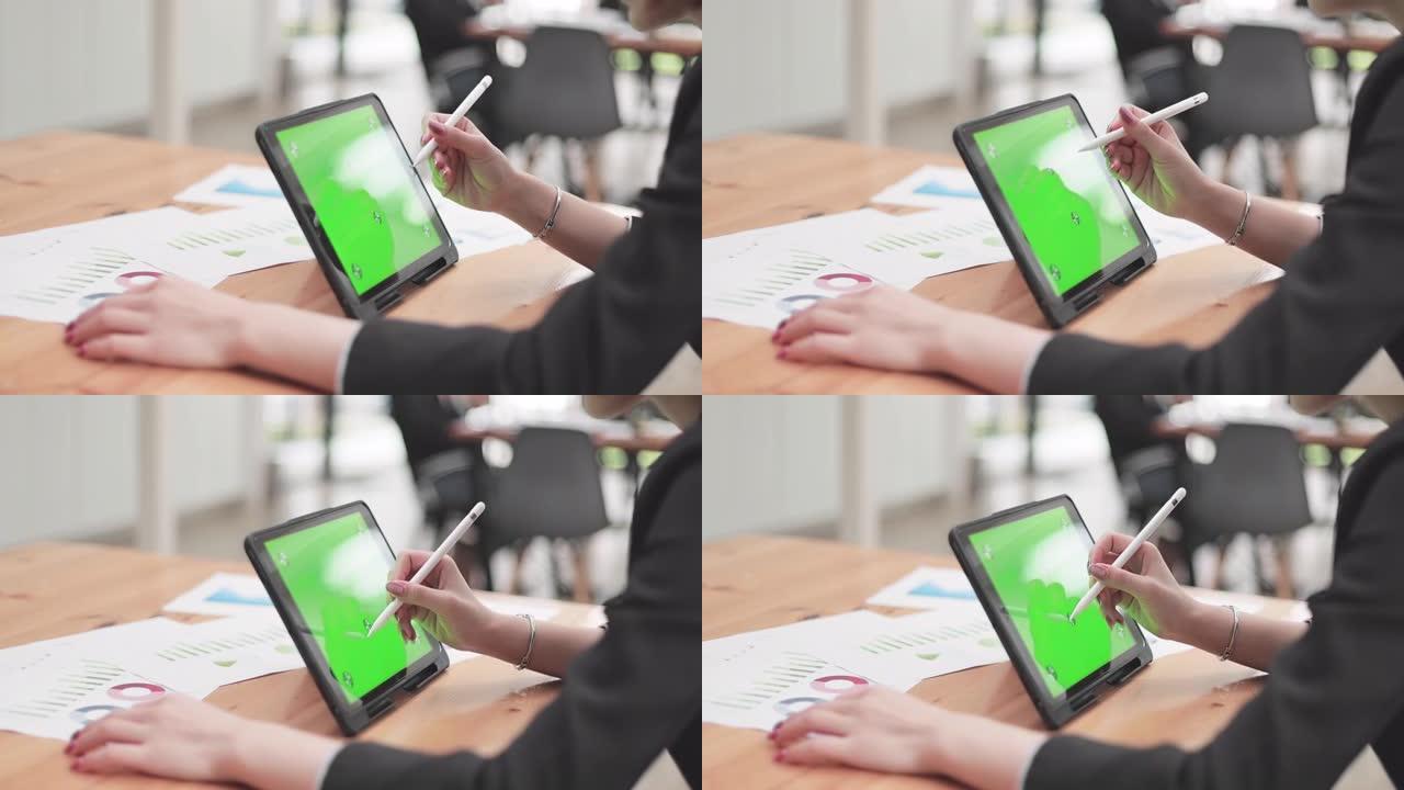 在带有绿色屏幕的数字平板电脑上书写的手的特写