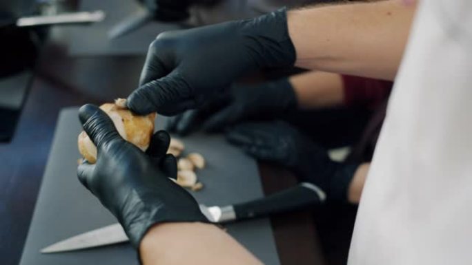男人的手戴着手套的特写镜头用刀烹饪食物去皮蘑菇