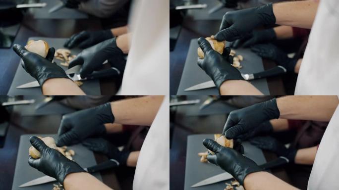 男人的手戴着手套的特写镜头用刀烹饪食物去皮蘑菇