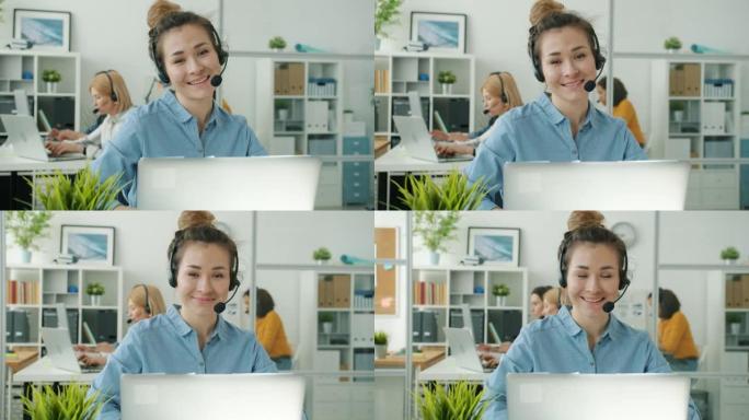 坐在呼叫中心办公室办公桌前戴着耳机的年轻亚洲女性的慢动作肖像