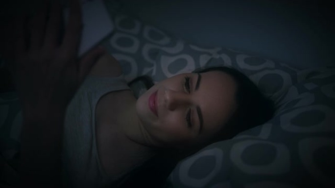 女人深夜在家床上使用手机