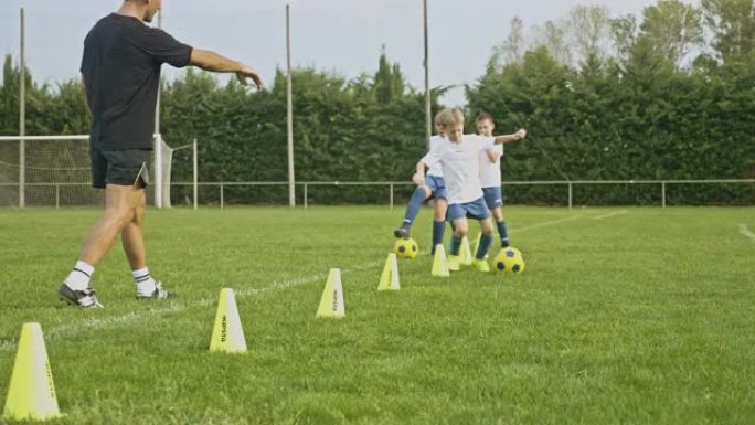 年轻的男孩和女孩足球运动员练习运球