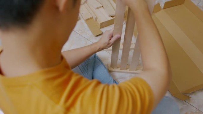 特写亚洲男子的手坐在地板上做家具在家里组装。
