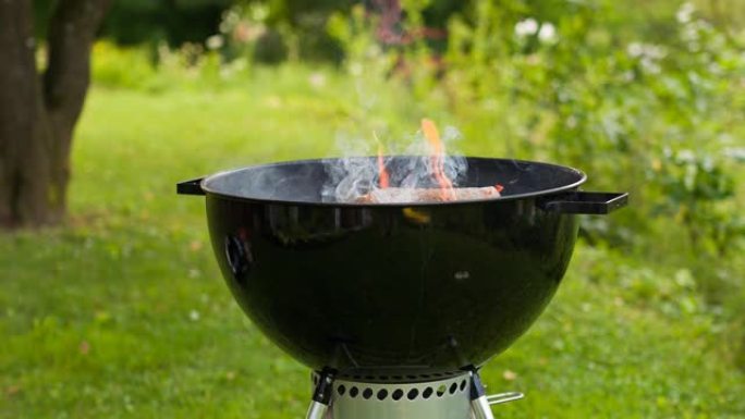 在烧烤烤架中燃烧木材，准备热煤在后院烧烤