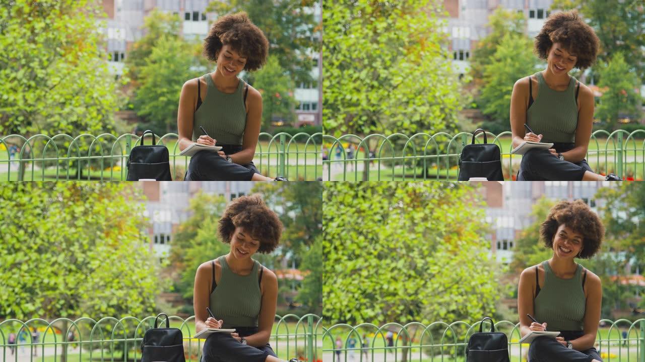 公园里的年轻女子坐在长凳上在笔记本上写字