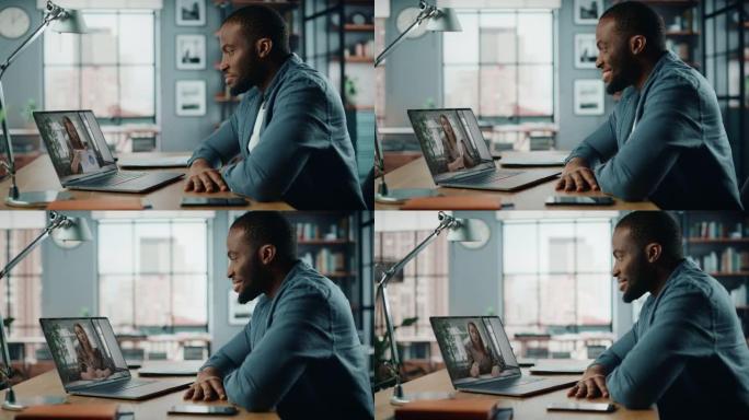 英俊的非洲裔美国男子坐在客厅的桌子后面，在台式电脑上进行视频通话。自由职业者在家工作，通过互联网与同