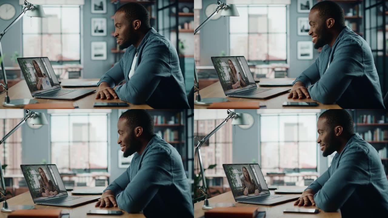 英俊的非洲裔美国男子坐在客厅的桌子后面，在台式电脑上进行视频通话。自由职业者在家工作，通过互联网与同