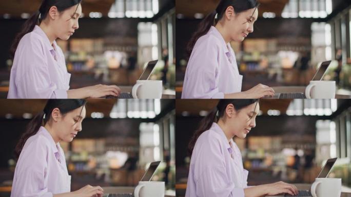 在咖啡馆使用笔记本电脑的亚洲妇女