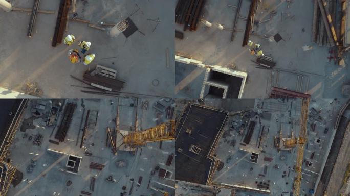 建筑工地的空中俯视图，由不同的工程师和工人组成，经纬仪抬头微笑。重型机械和建筑工人正在该地区工作。
