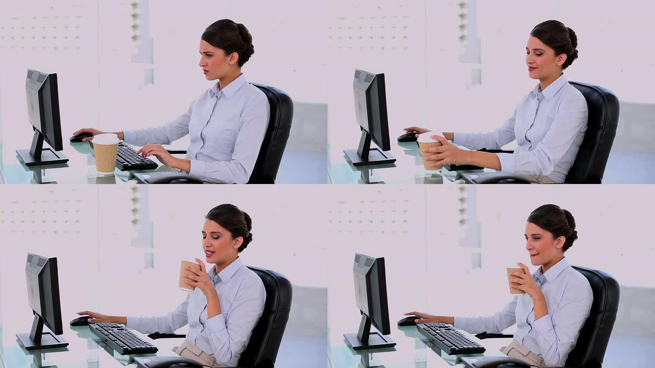 内容美丽的女商人使用电脑和享受咖啡